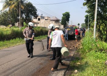 Polisi bersama warga bersihkan tumpahan solar di jalan di Cianjur (FOTO: Istimewa)