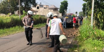 Polisi bersama warga bersihkan tumpahan solar di jalan di Cianjur (FOTO: Istimewa)
