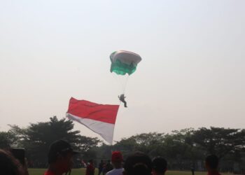 Pemerintah Kabupaten (Pemkab) Bogor menyuguhkan atraksi terjun payung yang membawa bendera merah putih, bendera Kabupaten Bogor, dan bendera KONI Kabupaten Bogor kepada masyarakat pada Minggu (11/8/24). (FOTO: Humas Pemkab Bogor)