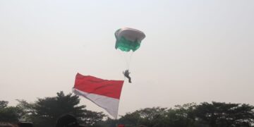 Pemerintah Kabupaten (Pemkab) Bogor menyuguhkan atraksi terjun payung yang membawa bendera merah putih, bendera Kabupaten Bogor, dan bendera KONI Kabupaten Bogor kepada masyarakat pada Minggu (11/8/24). (FOTO: Humas Pemkab Bogor)