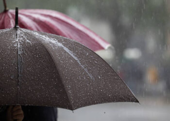 Particular view of a wet grey and red umbrellas after the rain