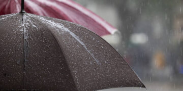 Particular view of a wet grey and red umbrellas after the rain