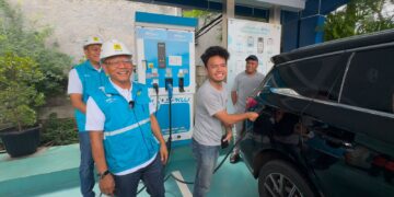 Pemudik kendaraan listrik, Ramdan (19) bersama ayahnya Sugeng, sedang mengisi daya kendaraan listrik ditemani General Manager PLN UID Jakarta Raya, Lasiran di SPKLU Rest Area KM 6 Jalan Tol Jakarta - Bekasi Timur.