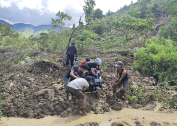 Warga bergotong royong membantu pengendara melintasi jalan yang tertutup material usai peristiwa tanah longsor terjadi di Kabupaten Mamasa, Provinsi Sulawesi Barat, Selasa (13/5). (BPBD Kabupaten Mamasa via BNPB)