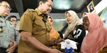 Warga Desa Mekarrahayu, Kecamatan Sumedang Selatan tersenyum bahagia ketika menerima kunci rumah baru dari Bupati Sumedang Dony Ahmad Munir, Senin (24/11/2025). (Foto: Humas Pemkab Sumedang)