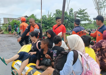 Foto : Sejumlah anggota BPBD bersama relawan mengevakuasi warga terdampak banjir menggunakan perahu karet di Kota Pekalongan, Minggu (18/1). (Foto: BNPB Via BPBD Janteng)