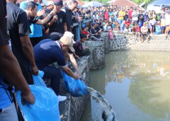 Bupati Kuningan Dian Rachmat Yanuar menabur ikan ke sungai untuk diburu warga.(Foto: Humas Pemkab Kuningan)