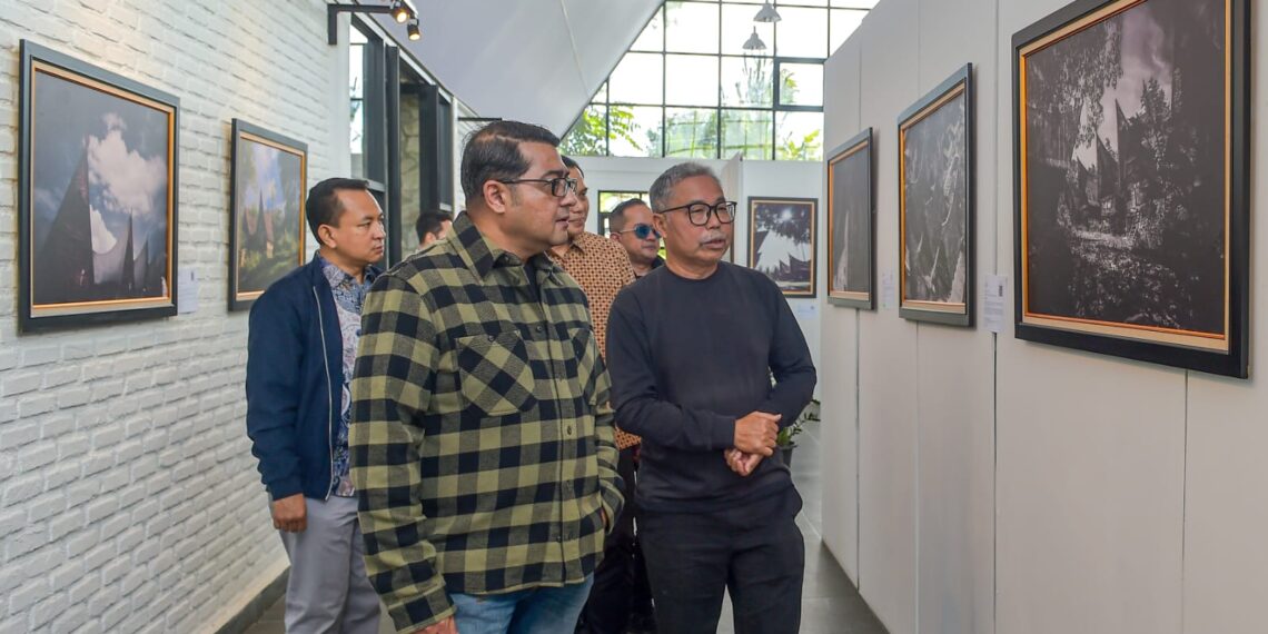 Menteri Ekonomi Kreatif/Kepala Badan Ekonomi Kreatif (Ekraf), Teuku Riefky Harsya (kiri), bersama Fotografer profesional sekaligus pendiri Huta Art Space, Edward Tigor Siahaan (kanan) mengamati foto pada pameran Toba Heritage Photo Exhibition 2026 di Huta Art Space, Sumatra Utara, Sabtu (11/7/2026).