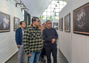 Menteri Ekonomi Kreatif/Kepala Badan Ekonomi Kreatif (Ekraf), Teuku Riefky Harsya (kiri), bersama Fotografer profesional sekaligus pendiri Huta Art Space, Edward Tigor Siahaan (kanan) mengamati foto pada pameran Toba Heritage Photo Exhibition 2026 di Huta Art Space, Sumatra Utara, Sabtu (11/7/2026).